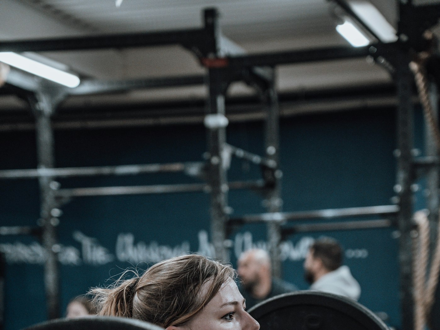 A member focused before lifting at the barbell rack in the training floor