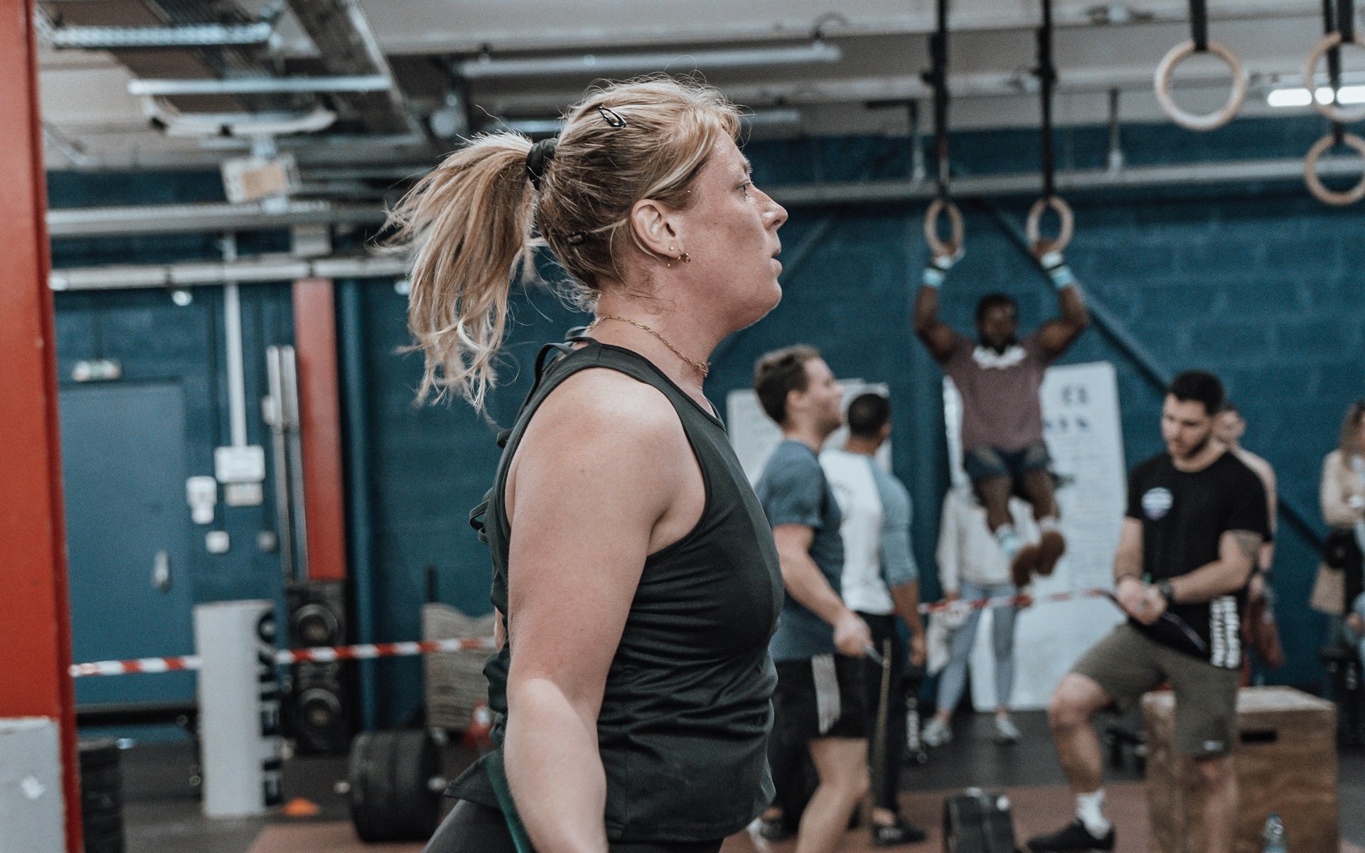Members mid-session on the club floor, one on the rings behind
